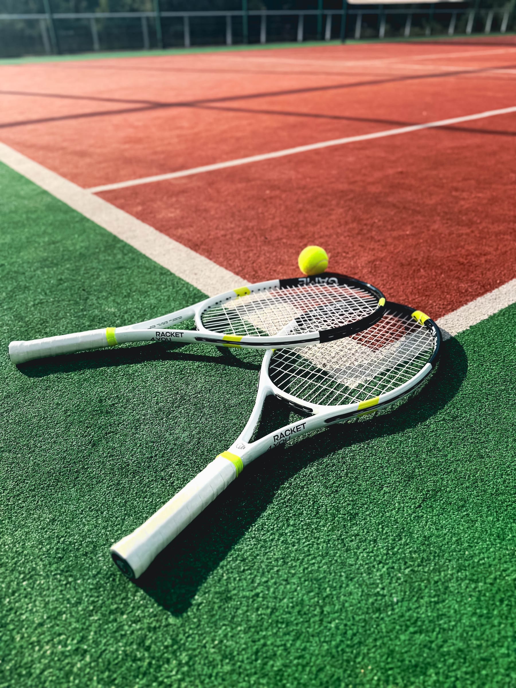 Two rackets and a ball on a green court