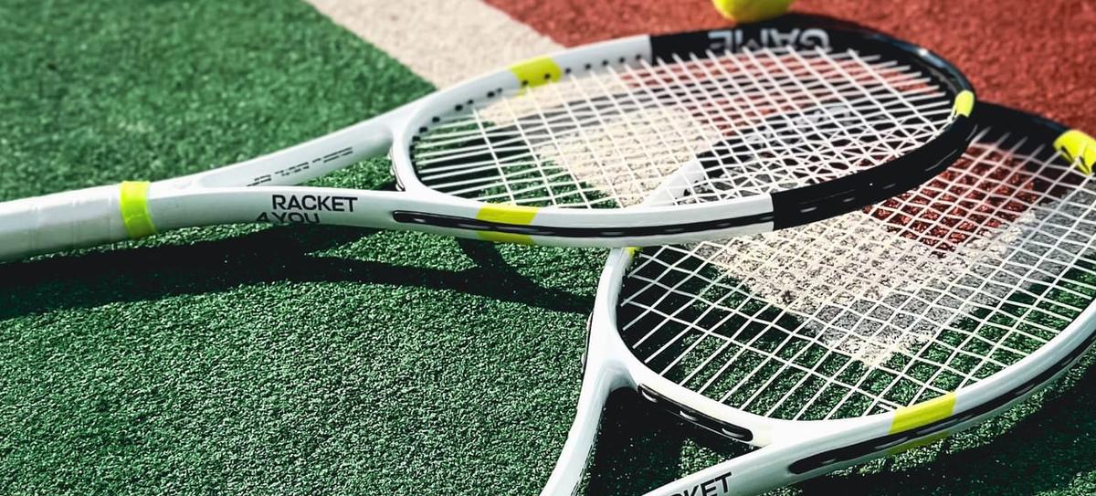 Two rackets and a ball on a green court
