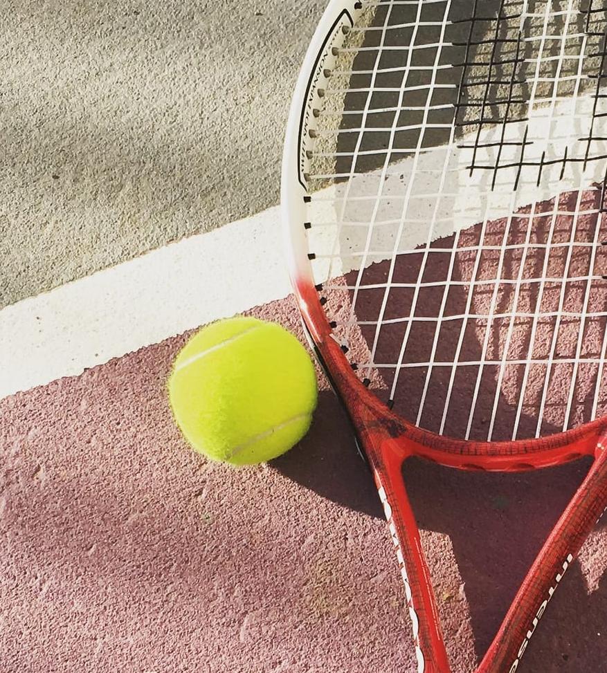 Red racket and tennis ball on a clay court