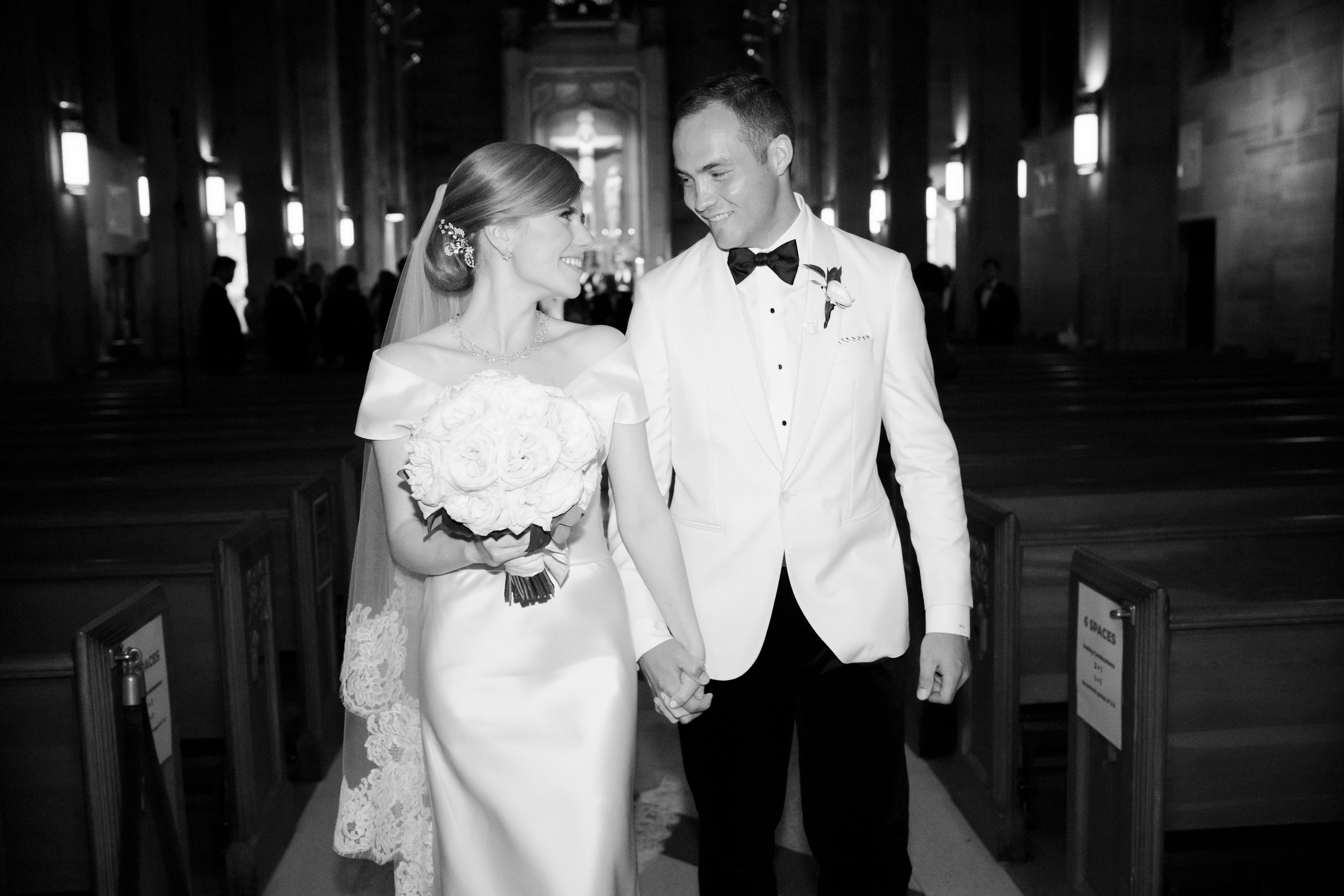 A bride and groom walk hand-in-hand down the aisle.