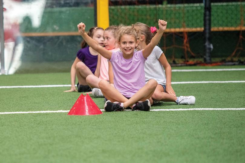 Kids sitting cross legged on the soccer field