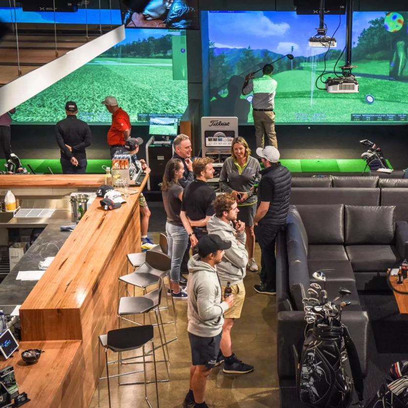 group of people at bar and golf simulators