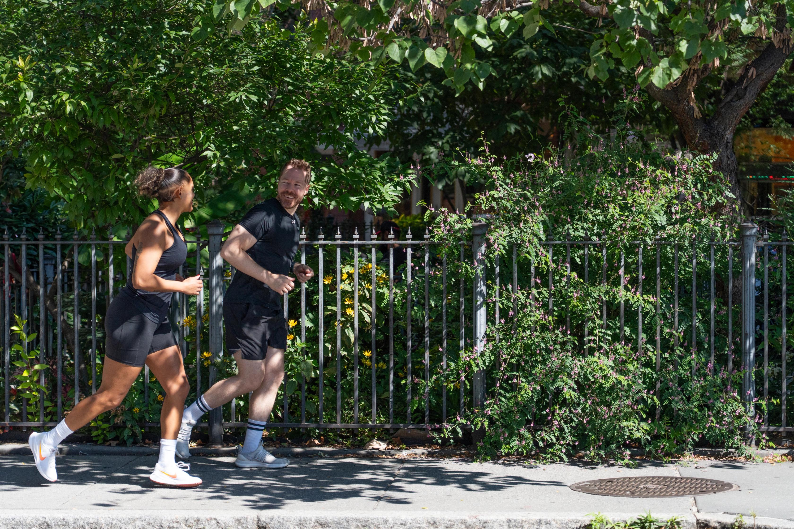 Two people jogging in vibrant green neighborhood 