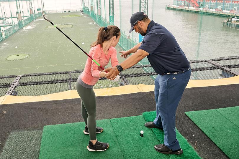 Golf pro helping woman with her swing