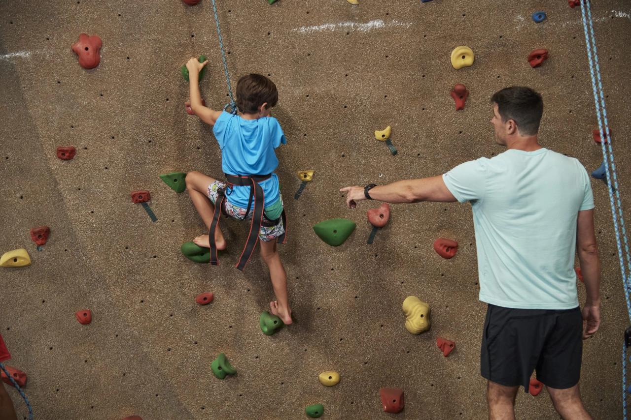 Boy rock climbing with a coach