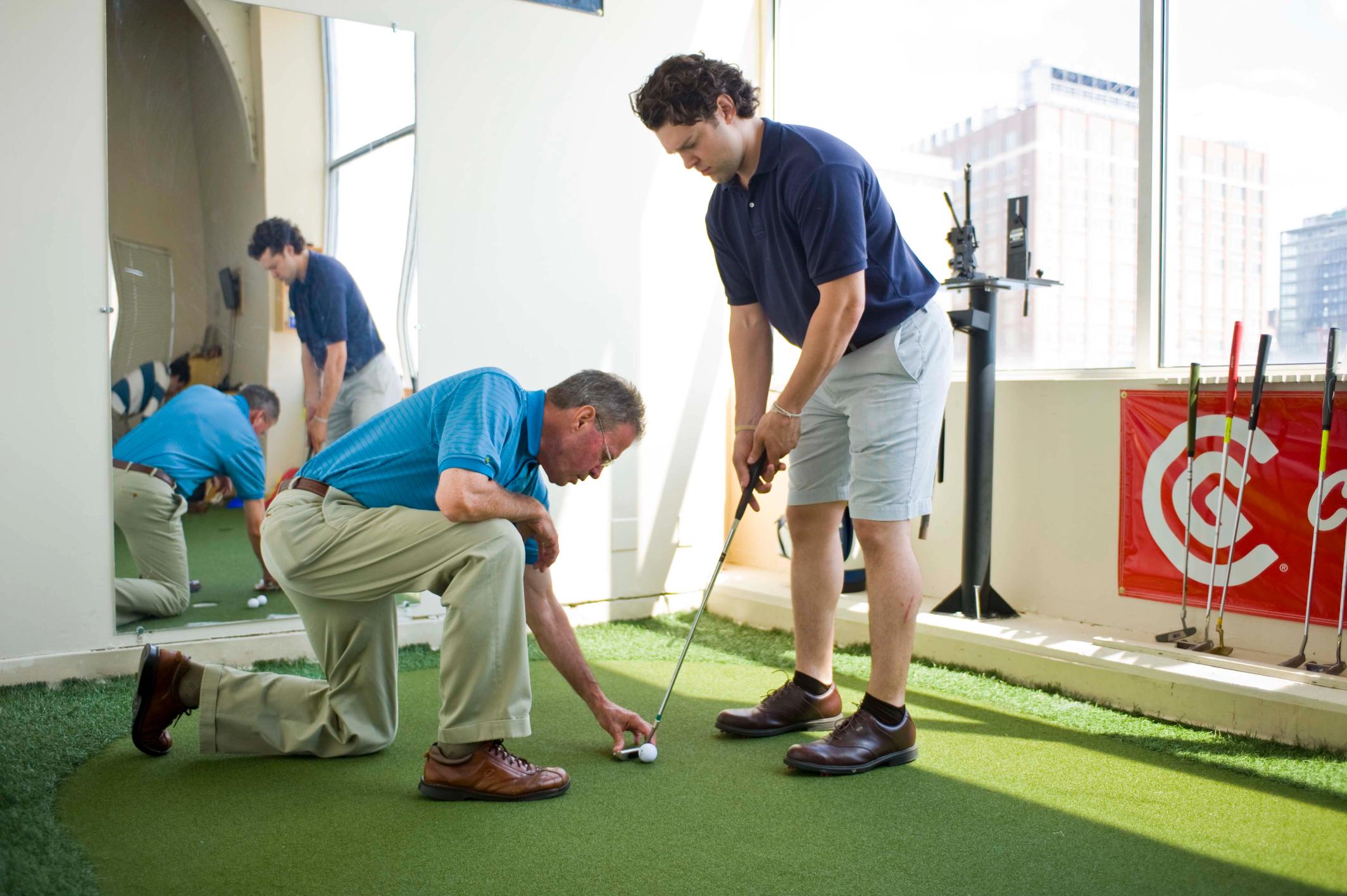Man working with coach in the golf putting studio 
