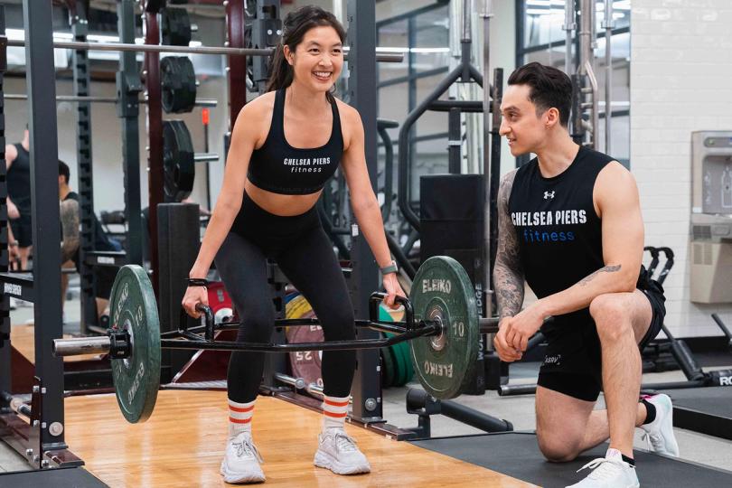 Girl lifting weights with a spotter