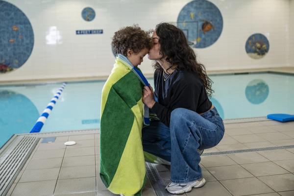 Kid and mom embracing on the pool deck