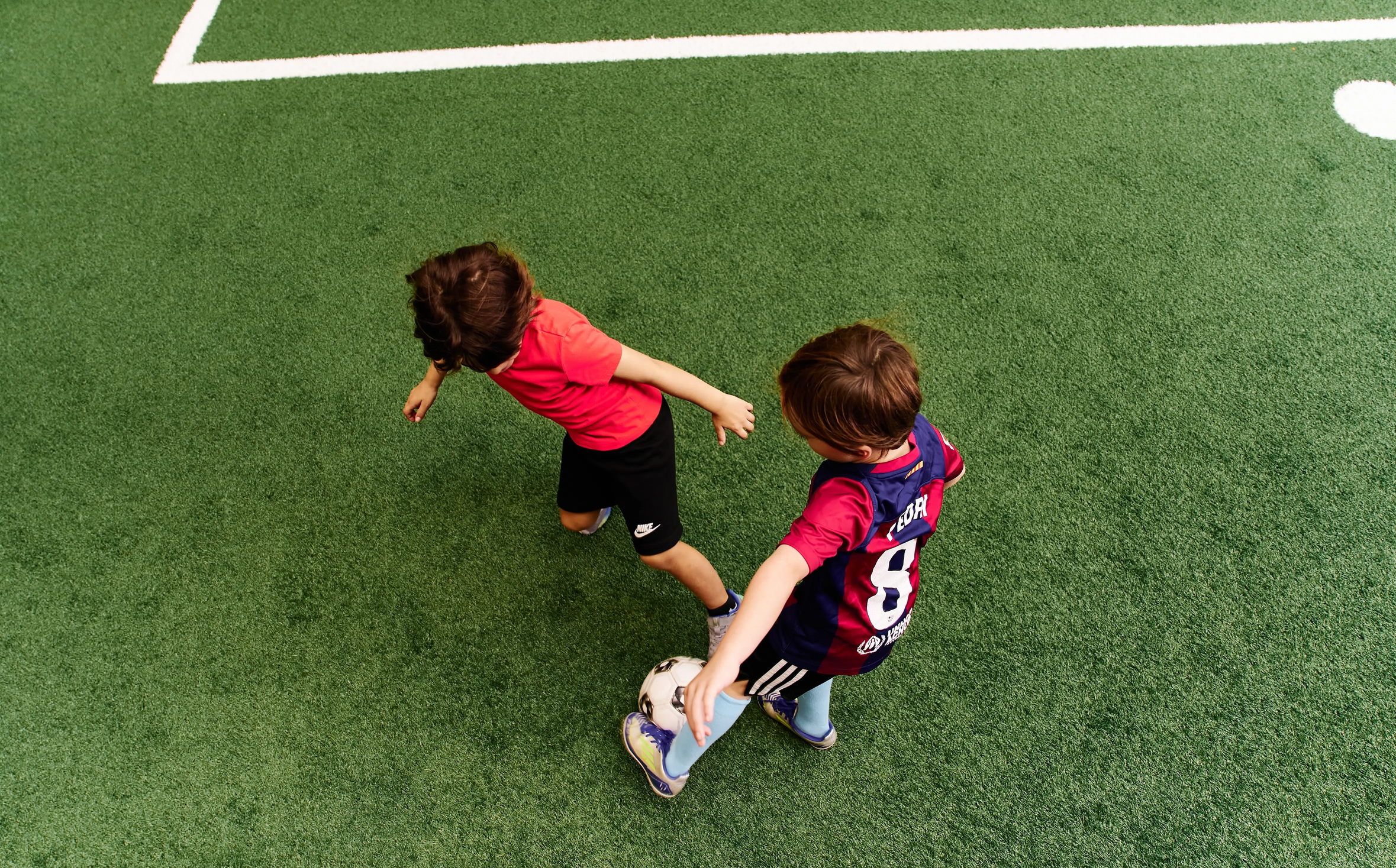 Two kids playing soccer on indoor turf field