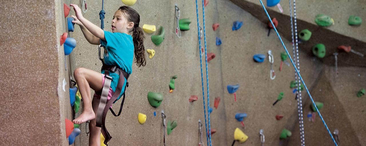 Kid bouldering up a rock wall