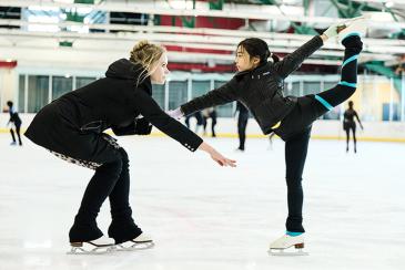Coach helping a kid figure skate