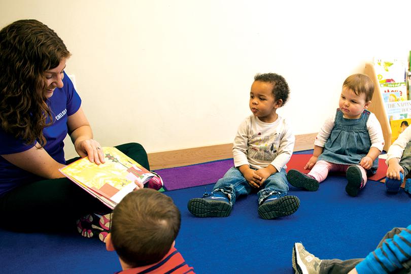 Toddlers gathering around a teacher for reading time