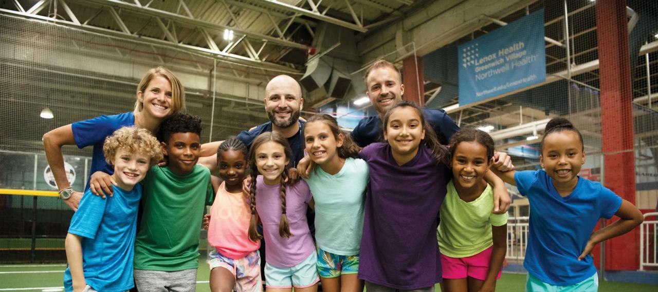 Group photo of happy kids and adults on a soccer field