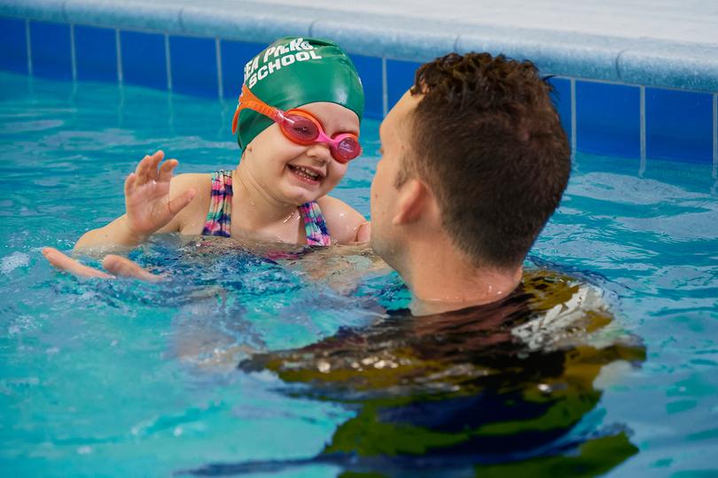 Kid swimming with a coach