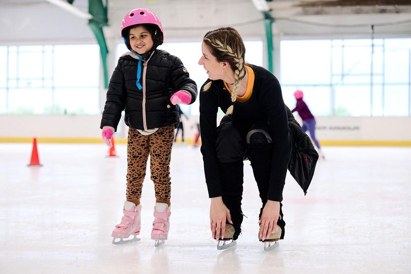 Coach helping a kid ice skate