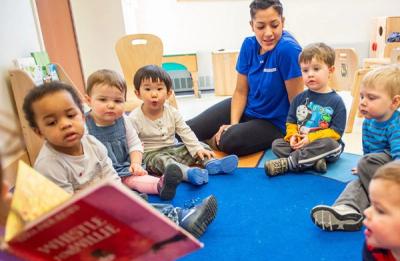 Toddlers gathering around a teacher for reading time