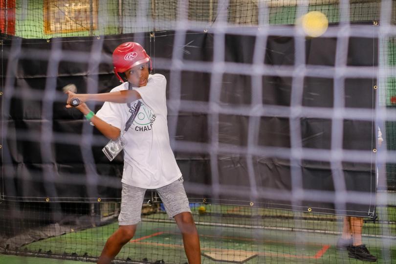 Boy hitting a softball in a batting cage