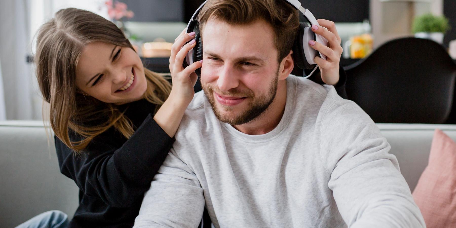 lány fejhallgatót tesz a férfira