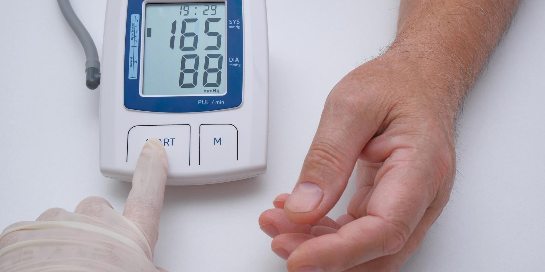 orvos idős férfi vérnyomását méri otthon