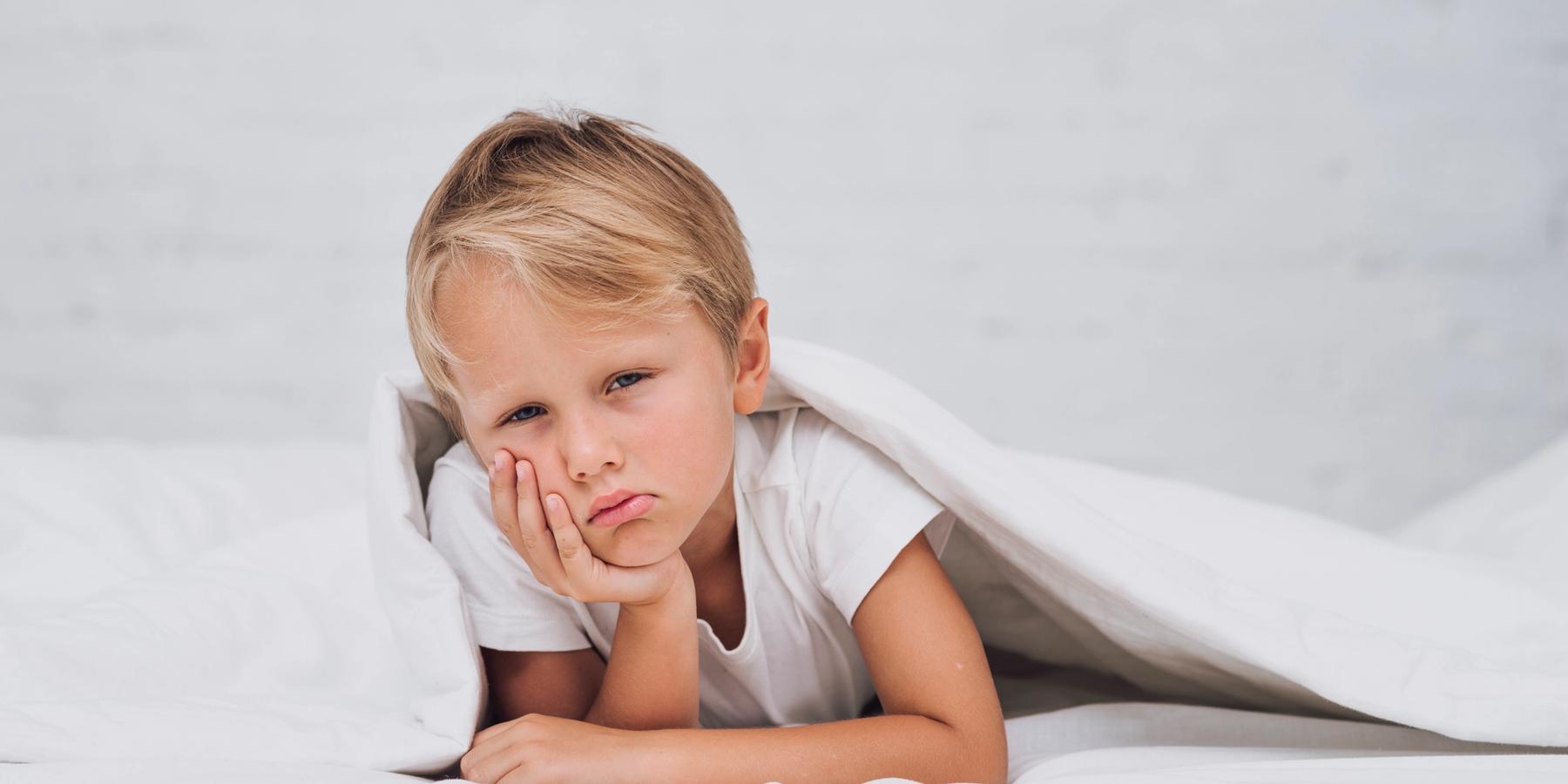 szomorú kisfiú ágyban