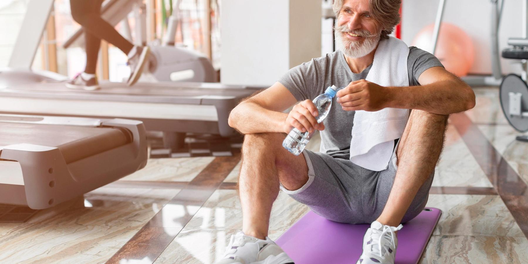 Középkorú férfi egy edzőteremben ül a jógamatracán