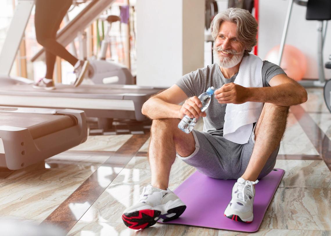 Középkorú férfi egy edzőteremben ül a jógamatracán