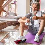 Középkorú férfi egy edzőteremben ül a jógamatracán