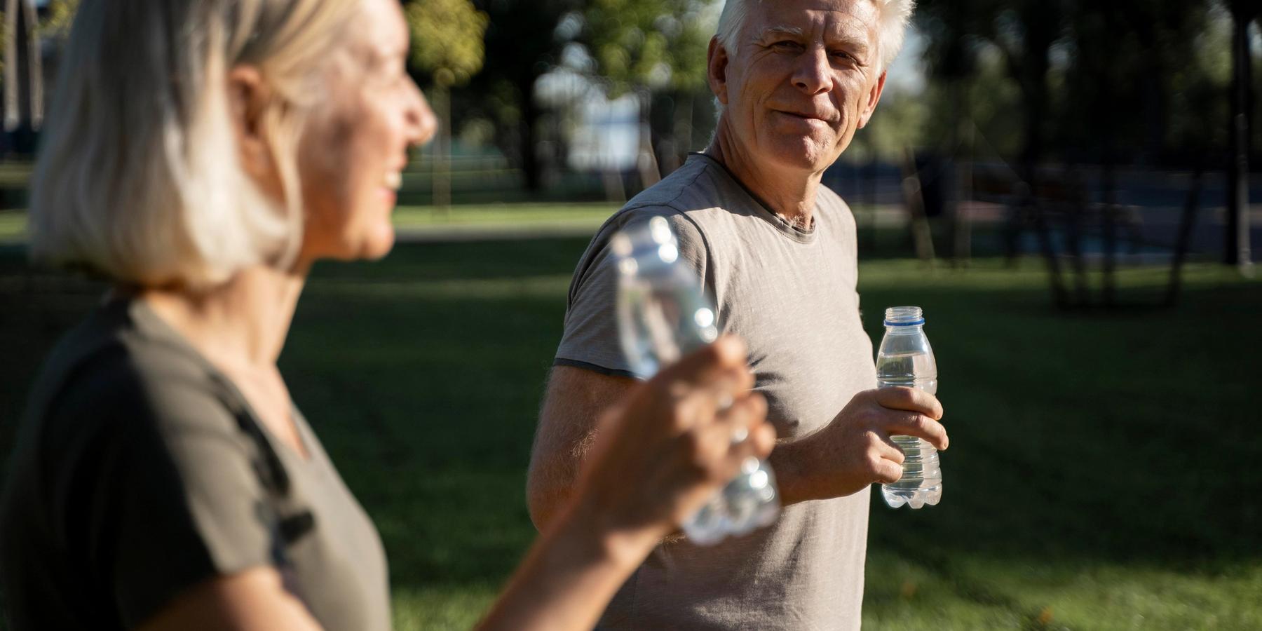 Oldalnézetű kép egy szabadban vizet ivó idősödő párról