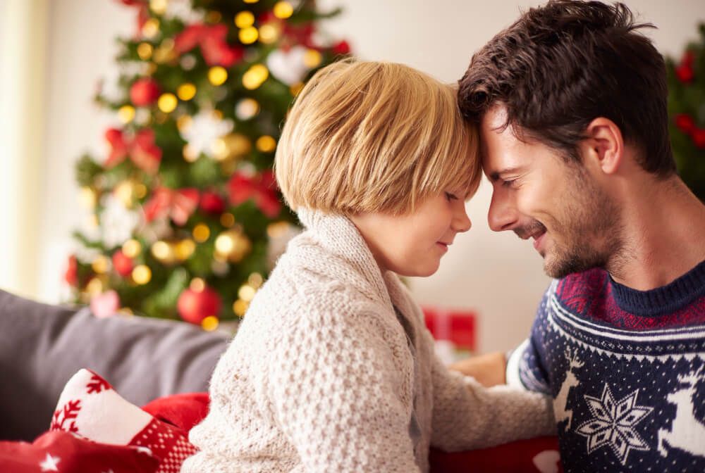 Apuka és gyermeke közötti szeretetteljes pillanat, a háttérben karácsonyfa