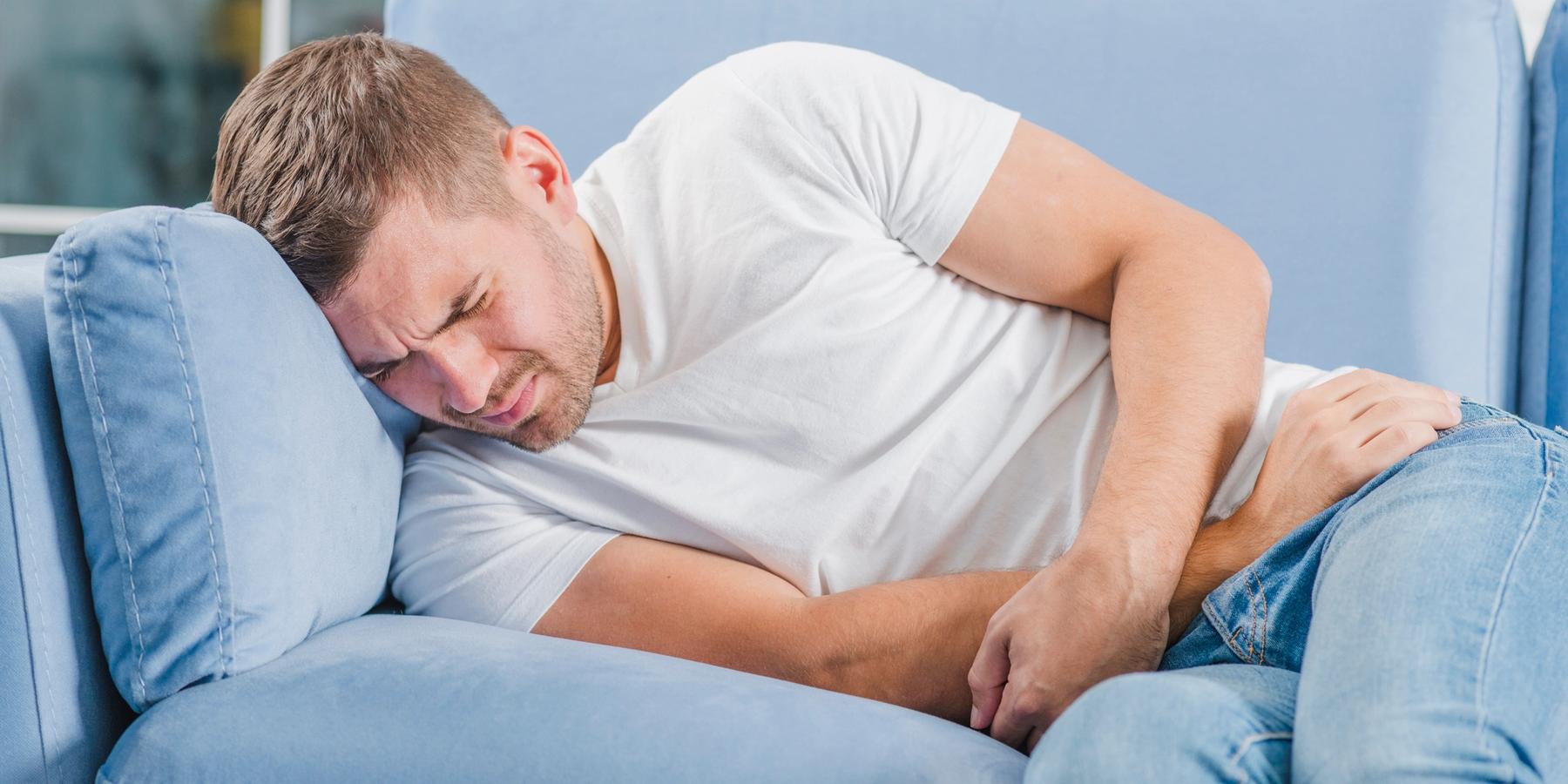 kanapén fekvő férfinak komoly kismedencei fájdalma van