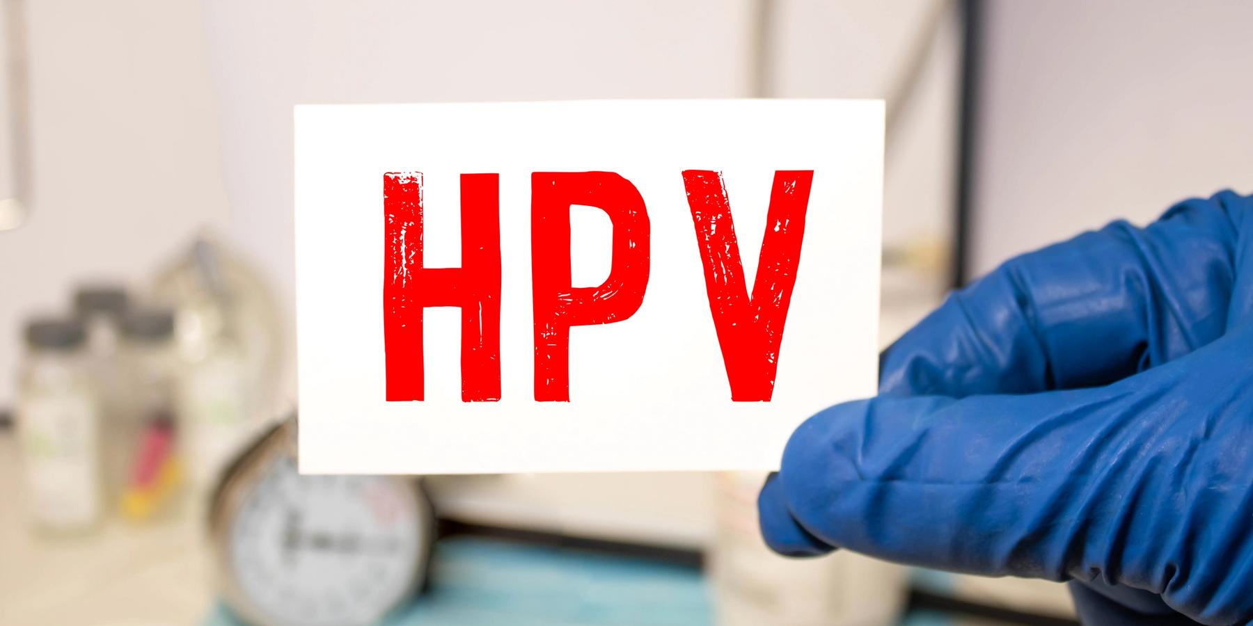 HPV szó írva egy papírra, háttérben orvosi mappa, beteg fájlokkal, tabletták és sztetoszkóp