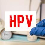 HPV szó írva egy papírra, háttérben orvosi mappa, beteg fájlokkal, tabletták és sztetoszkóp