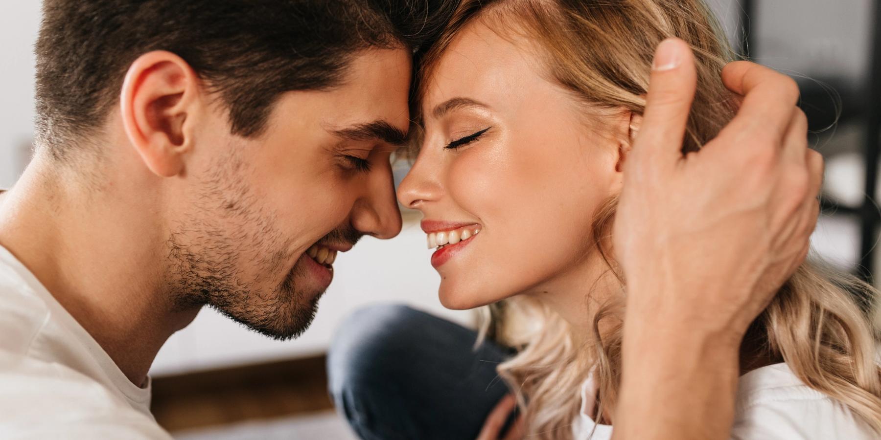 Fiatal szerelmes pár csukott szemmel, mosolyogva, boldogan érinti össze a homlokát