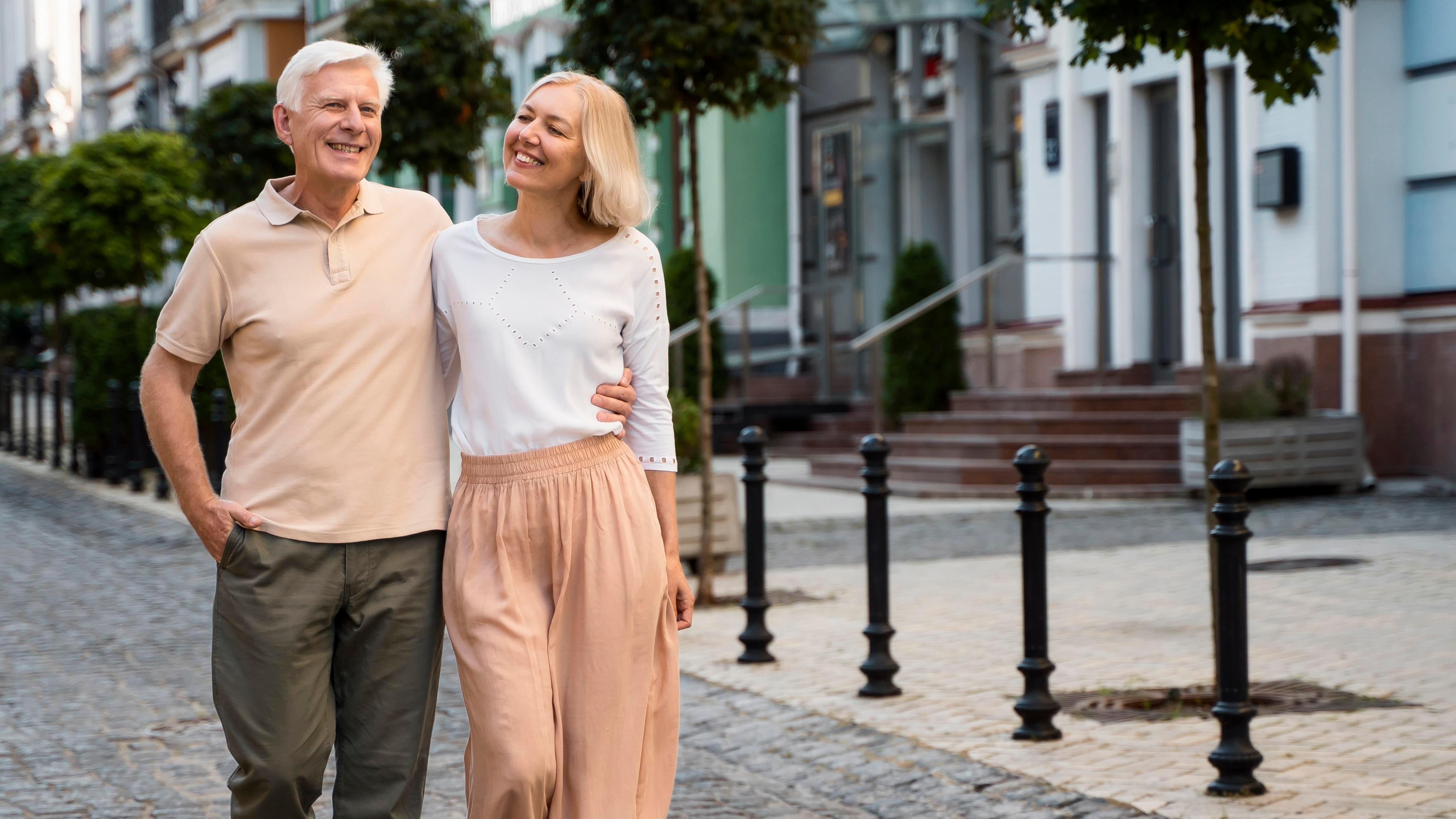 boldog idős pár fotója elölnézetből ahogy sétálnak a városban