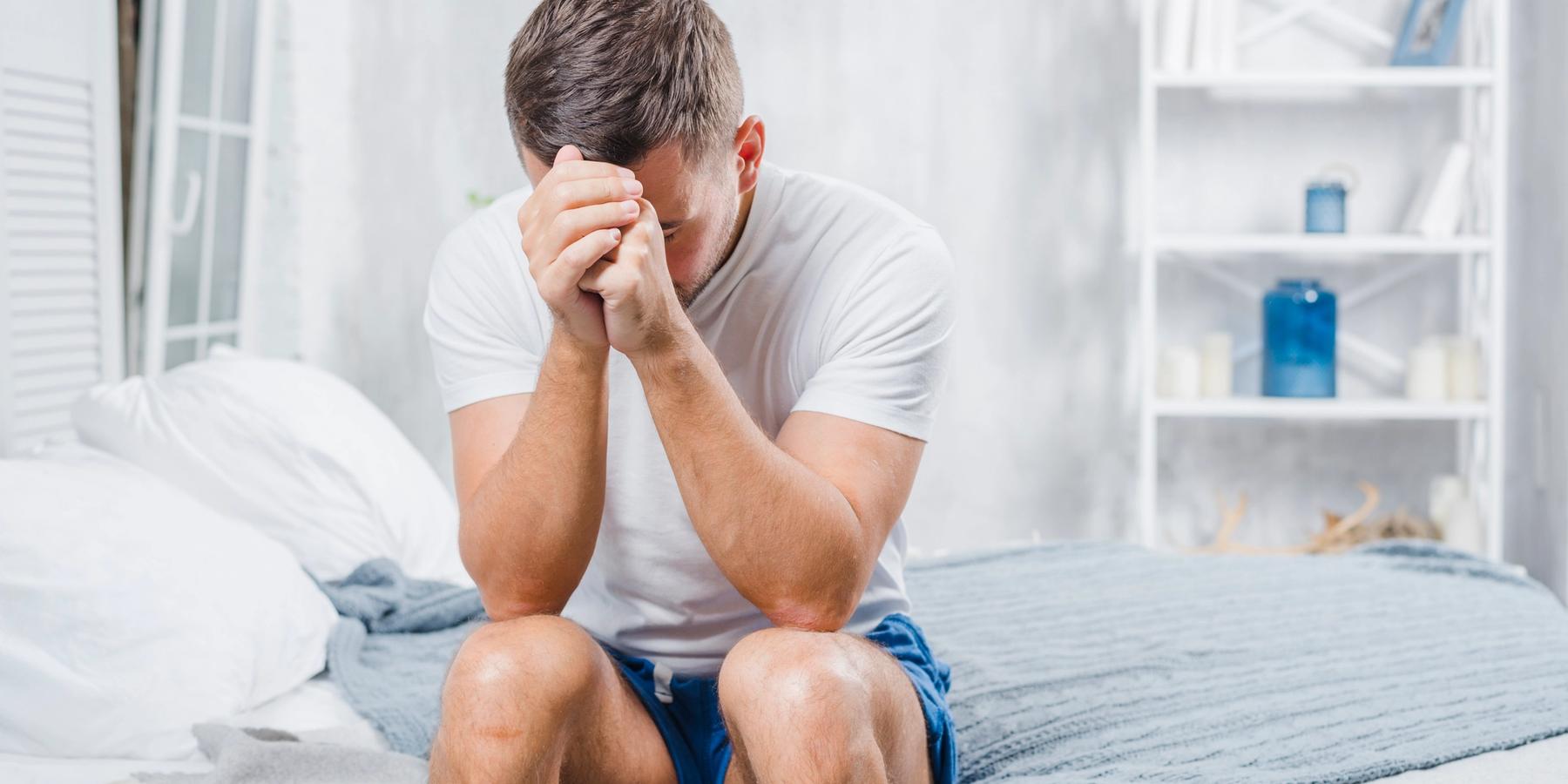 frusztrált férfi ül az ágyon