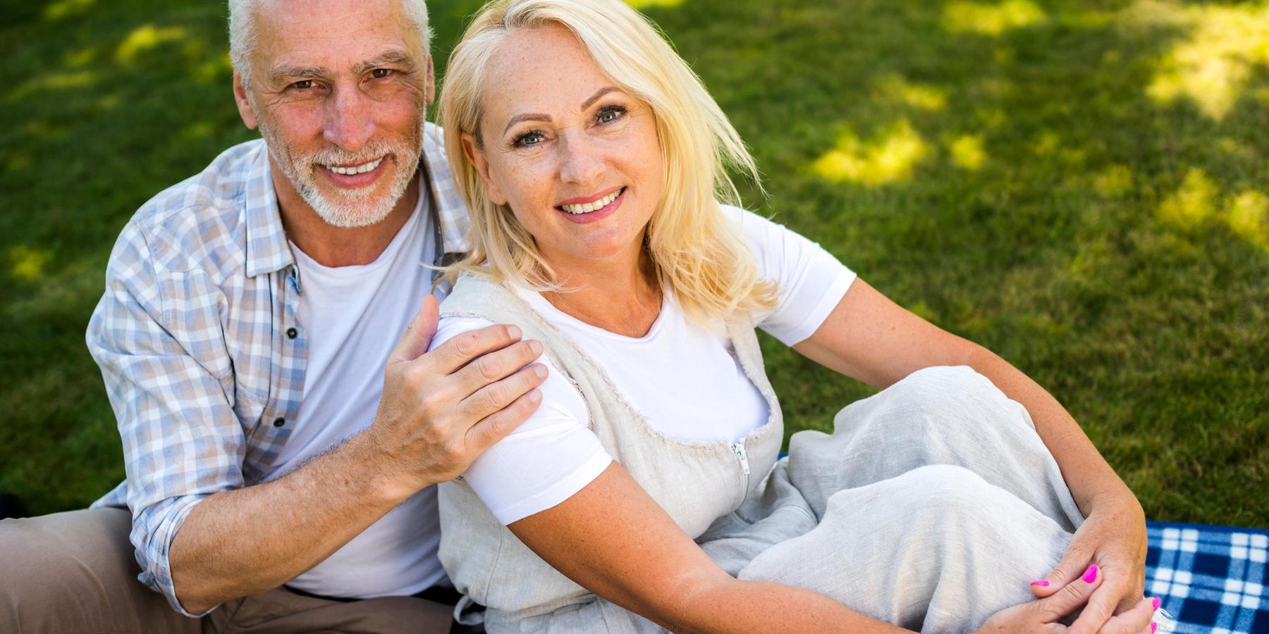 Pokrócon, a szabadban ülő középkorú, mosolygó pár