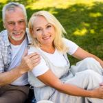 Pokrócon, a szabadban ülő középkorú, mosolygó pár