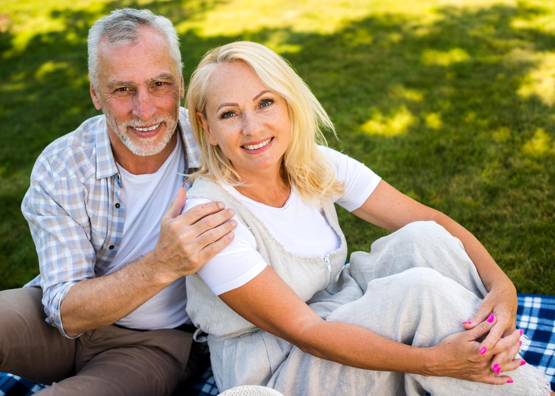 Pokrócon, a szabadban ülő középkorú, mosolygó pár
