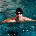 Úszósapkás, úszószemüveges férfi a medencében