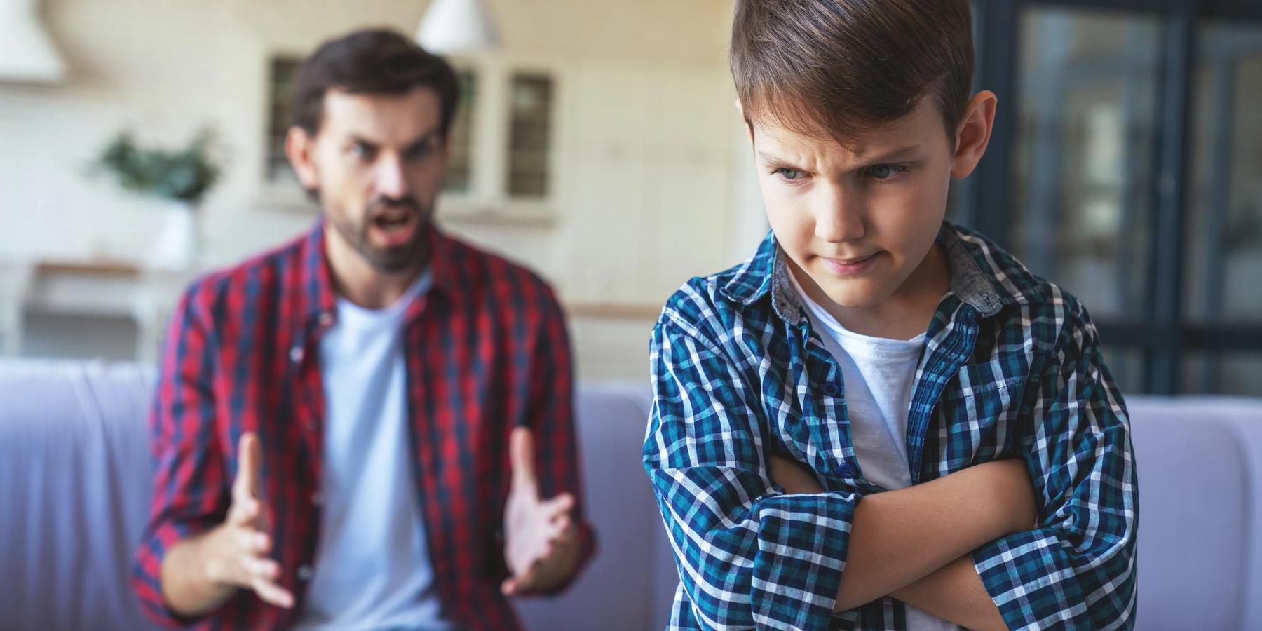 Egy dühös apa veszekszik fiával a nappaliban.