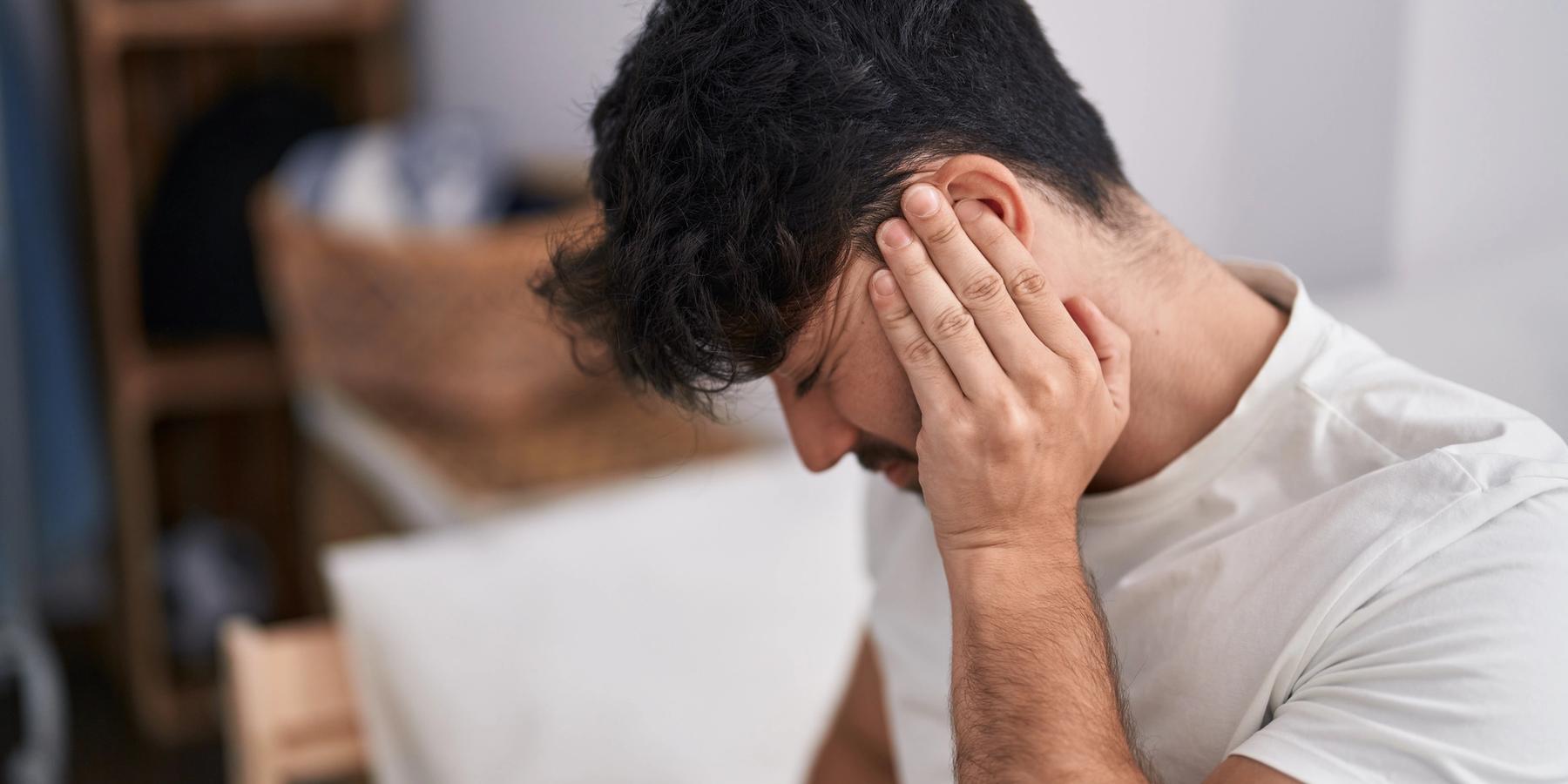 Fiatal spanyol férfi szenvedve ül az ágyon