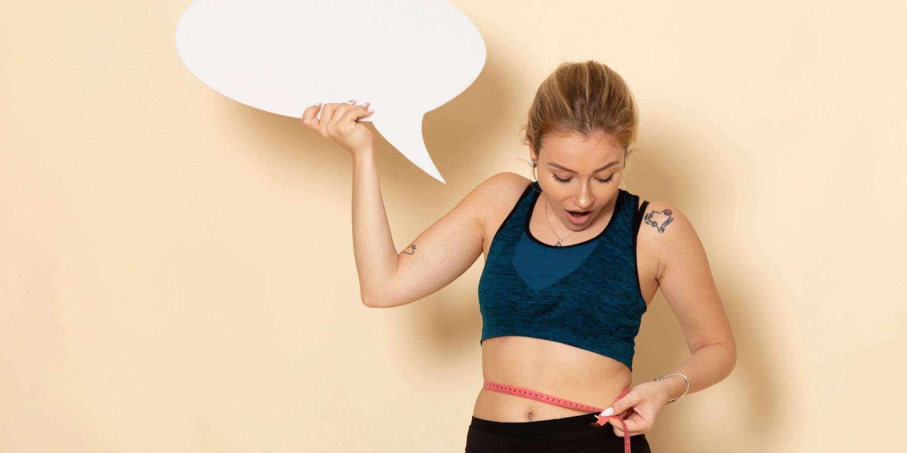 Fiatal nő sportruházatban, fehér szövegbuborékot tartva az egyik kezében, másik kezével a derekát mérve