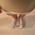 Túlsúlyos férfi áll a mérlegen