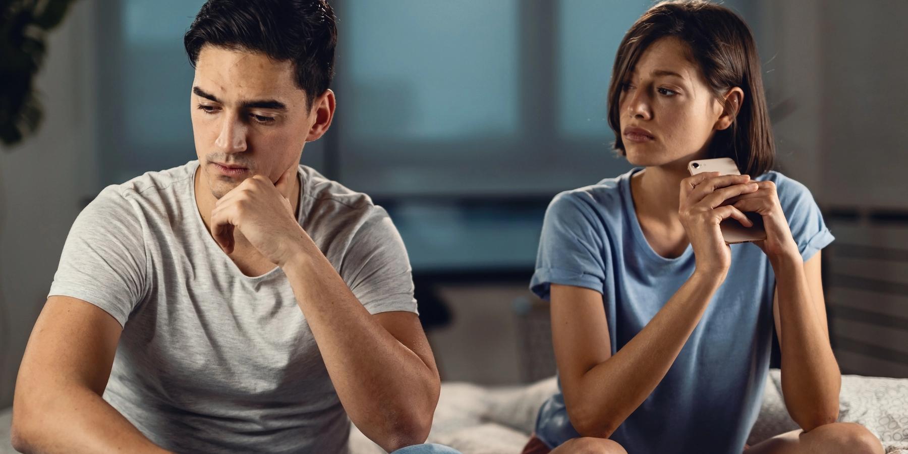 Fiatal aggódó férfi gondolkodik valamin, miközben barátnője mellett ül, és kapcsolati problémái vannak vele