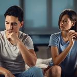 Fiatal aggódó férfi gondolkodik valamin, miközben barátnője mellett ül, és kapcsolati problémái vannak vele