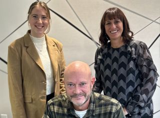 Courtney, Joe, and Julie standing in front of wall with patterned wallpaper