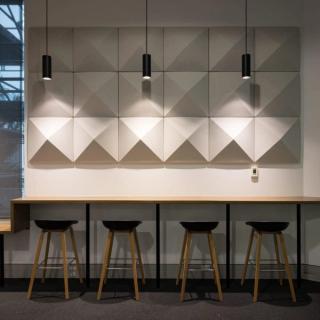 Beige acoustic 3d square tiles mounted on wall by seating area