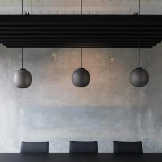 Three hanging globe lights with acoustic baffle system in background
