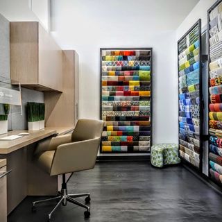 Two walls of sample fabrics and a desk with a chair