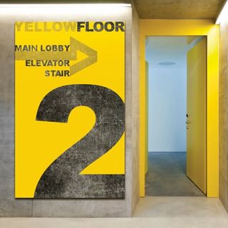 Yellow sign on wall indicating floor 2 and elevator